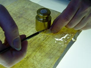 Image of a conservator repairing a parchment document with goldbeater's skin