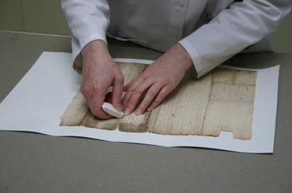 Image of a conservator mechanically cleaning a document