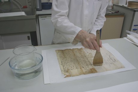 Image of a conservator resizing a document with gelatine