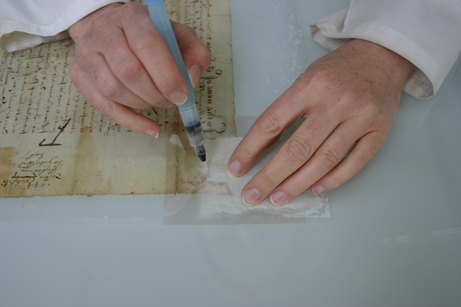 Image of a conservator tracing the missing area of a document onto Japanese paper using a water pen